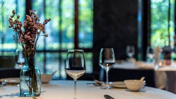 A dining table with a glass of water, a vase with flowers, and a bowl.
