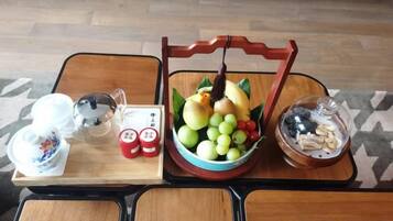 A table with a tray containing a bowl of fruit, a teapot, cups, and a small bowl of nuts.