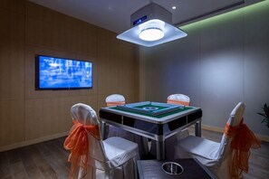 Una habitación con mesa de billar, cuatro sillas, televisor e iluminación en el techo.