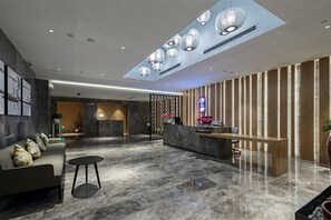 Un hall d’entrée moderne avec un comptoir d’accueil, un espace salon et une grande fenêtre.