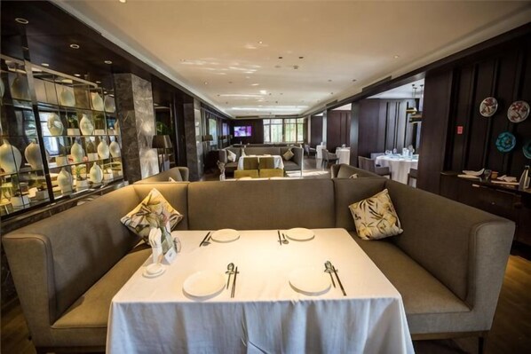 A dining area with a table set for four, a sofa, and a decorative vase. - Sunshine Peninsula Jinsha Hotel (Zhangjiagang)