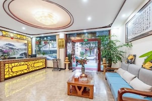 Un vestíbulo de hotel con mostrador de recepción, zona de estar y un amplio ventanal.