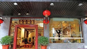 A traditional Chinese restaurant with a wooden facade, red lanterns, and a sign with Chinese characters.