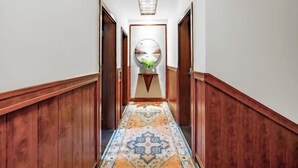 A hallway with wooden paneling, a patterned carpet, and a central decorative piece.