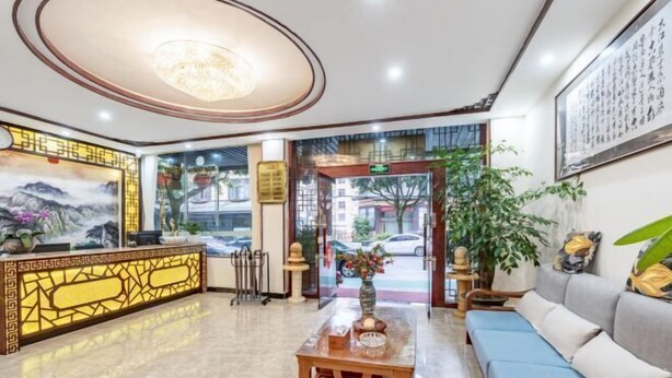 A hotel lobby with a reception desk, seating area, and a large window offering a view of the street.