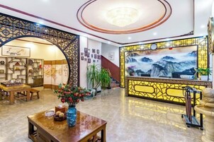 Un vestíbulo de hotel con mostrador de recepción, zona de estar y un cuadro grande en la pared.