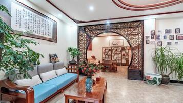 Un salón con un sofá azul, una mesa de centro de madera y un arco decorativo que da a un comedor.