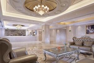 Un vestíbulo amplio con mostrador de recepción, un candelabro, un sofá y una mesa de centro.