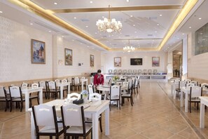 A spacious dining area with multiple tables and chairs, a central counter, and a chandelier. - Vienna International Hotel (Taoyuan Longba) (Taoyuan)