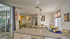 Una cocina con encimera de granito, armarios blancos y una zona de comedor con mesa y sillas.