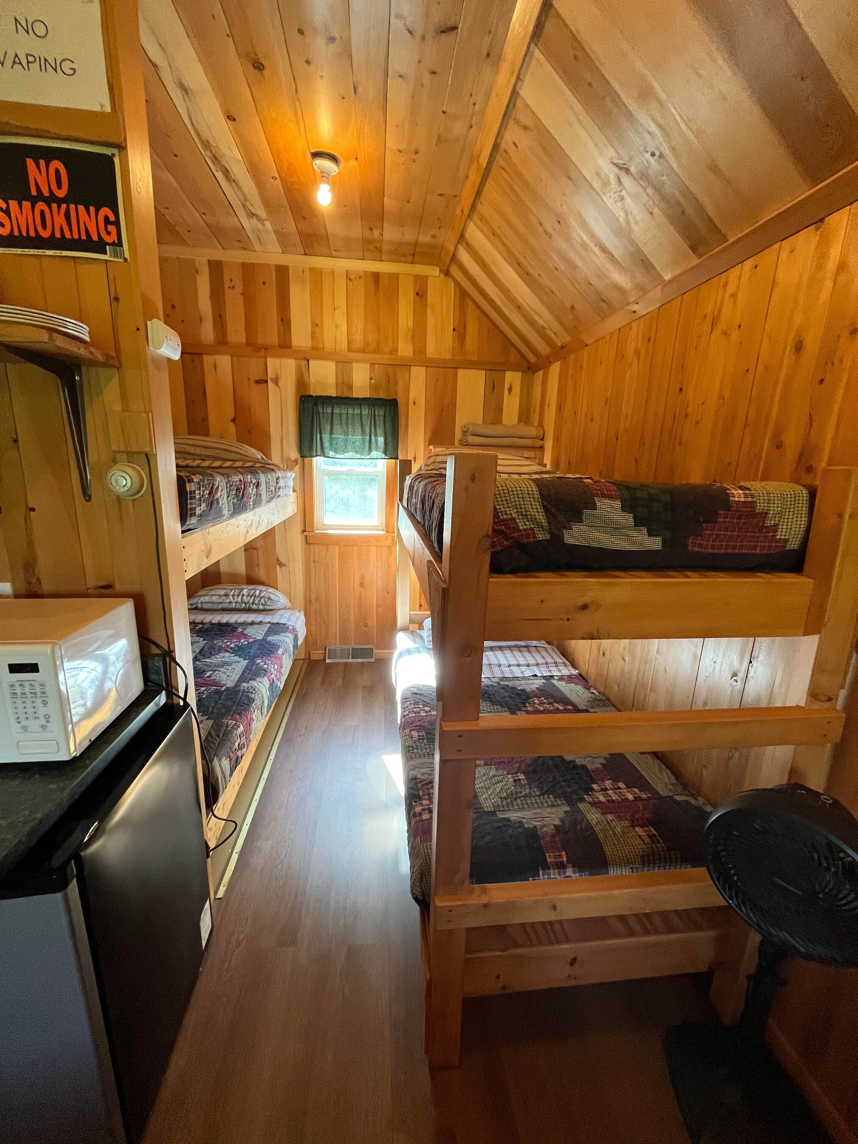 A cabin-style room with bunk beds, a microwave, and a 'No Smoking' sign.