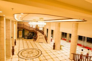 A spacious lobby with a grand staircase, marble flooring, and a central fountain. - Wenhe Hotel (Hepu)