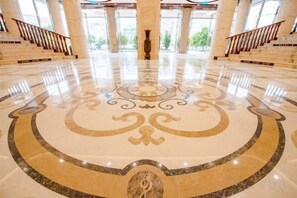 A spacious lobby with a polished marble floor, a grand staircase, and large windows allowing natural light. - Wenhe Hotel (Hepu)