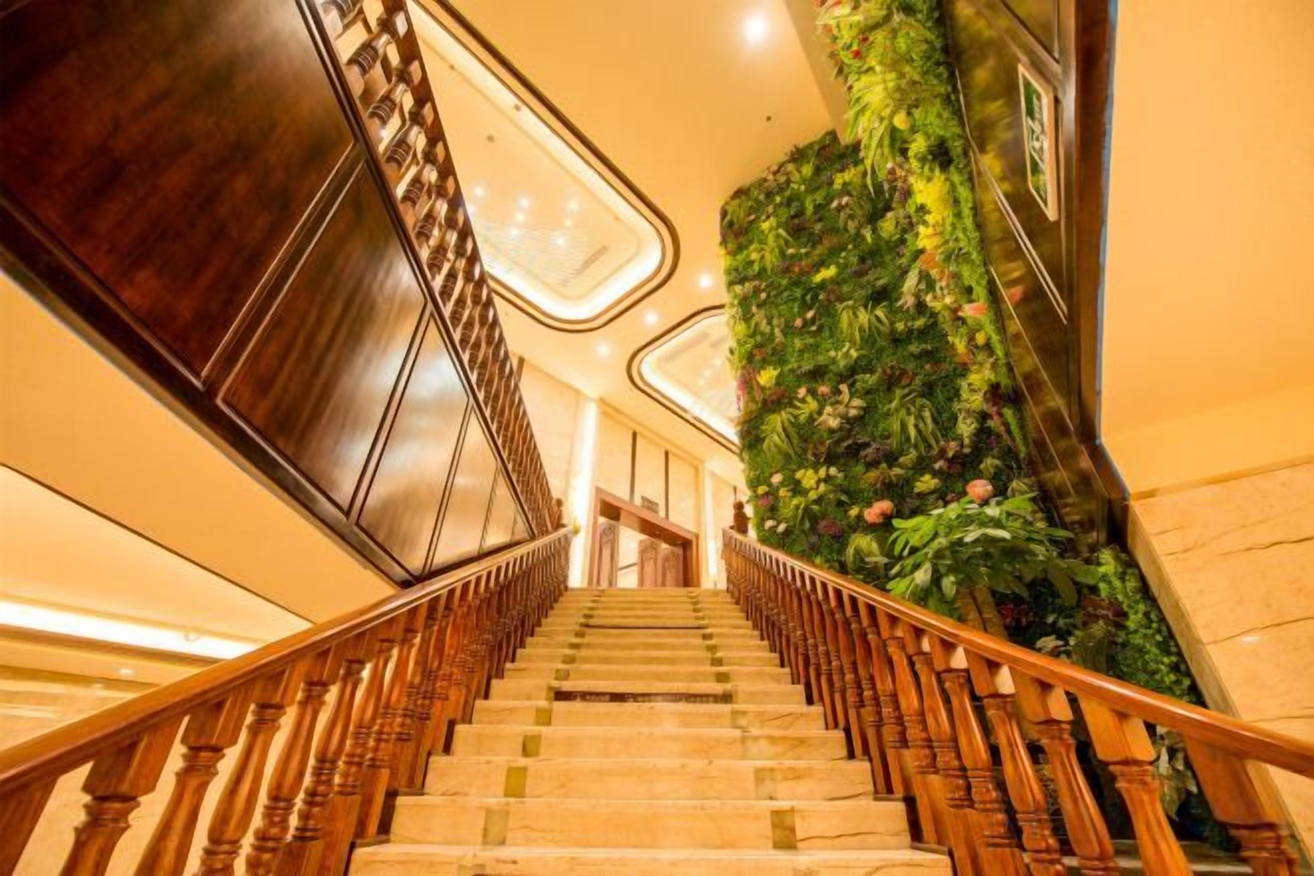 A staircase with wooden railings and a green wall with plants.