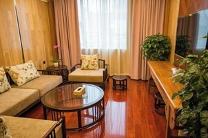Una sala de estar acogedora con sofá, sillón y una mesa redonda para café. Hay un banco de madera y una planta en maceta.