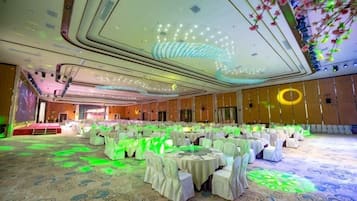 A banquet hall with round tables, chairs, and a carpeted floor.