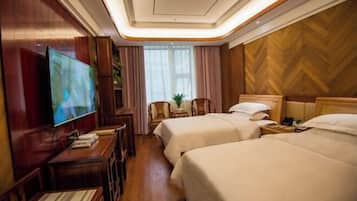 A hotel room with two beds, a TV, a desk, and a wooden wall.