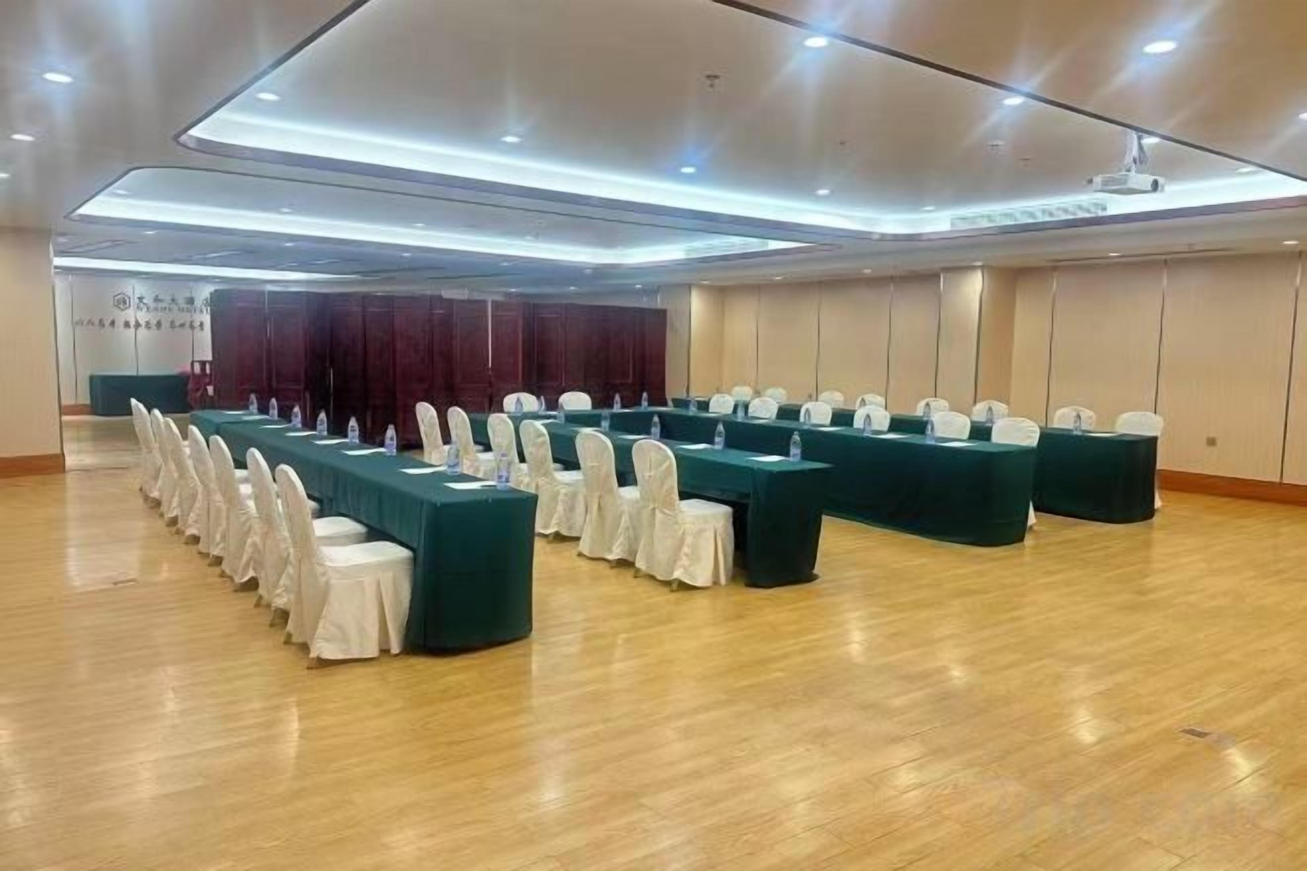 A conference room with long tables, chairs, and a wooden floor.