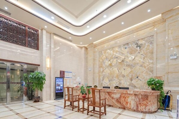 A hotel reception area with a marble reception desk, wooden chairs, and potted plants. - Wenhe Hotel (Hepu)