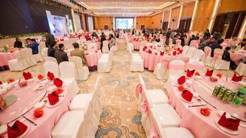 A banquet hall with round tables, white chairs, and pink tablecloths.