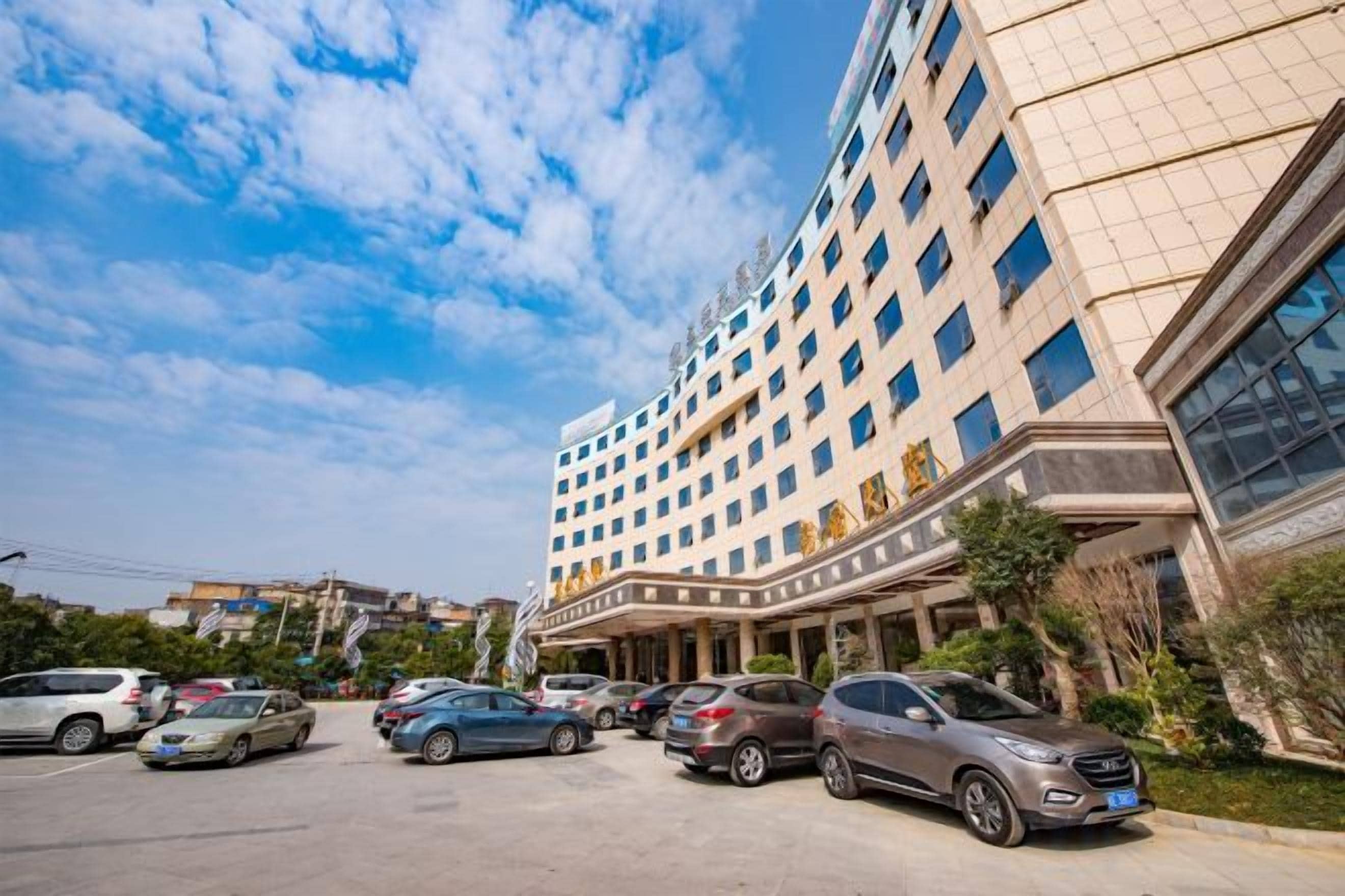 A multi-story hotel with a parking lot in front.