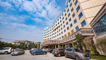 A multi-story hotel with a parking lot in front.