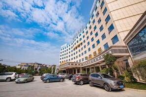 A multi-story hotel with a parking lot in front. - Wenhe Hotel (Hepu)