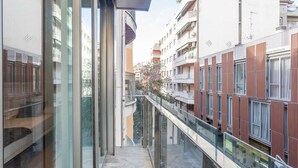 A modern building with a glass balcony, a stone floor, and a view of adjacent buildings. - Lovely apartment with big private terrace in Sant Gervasy for monthly rentals (Barcelona)