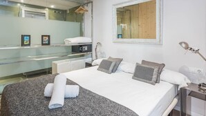 A modern hotel room with a large bed, a mirror, a bedside table, and a wardrobe. - Lovely apartment with big private terrace in Sant Gervasy for monthly rentals (Barcelona)