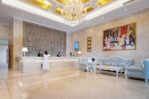 A hotel lobby with a reception desk, seating area, and artwork on the walls. - Vienna Hotel (Luhe) (Luhe)