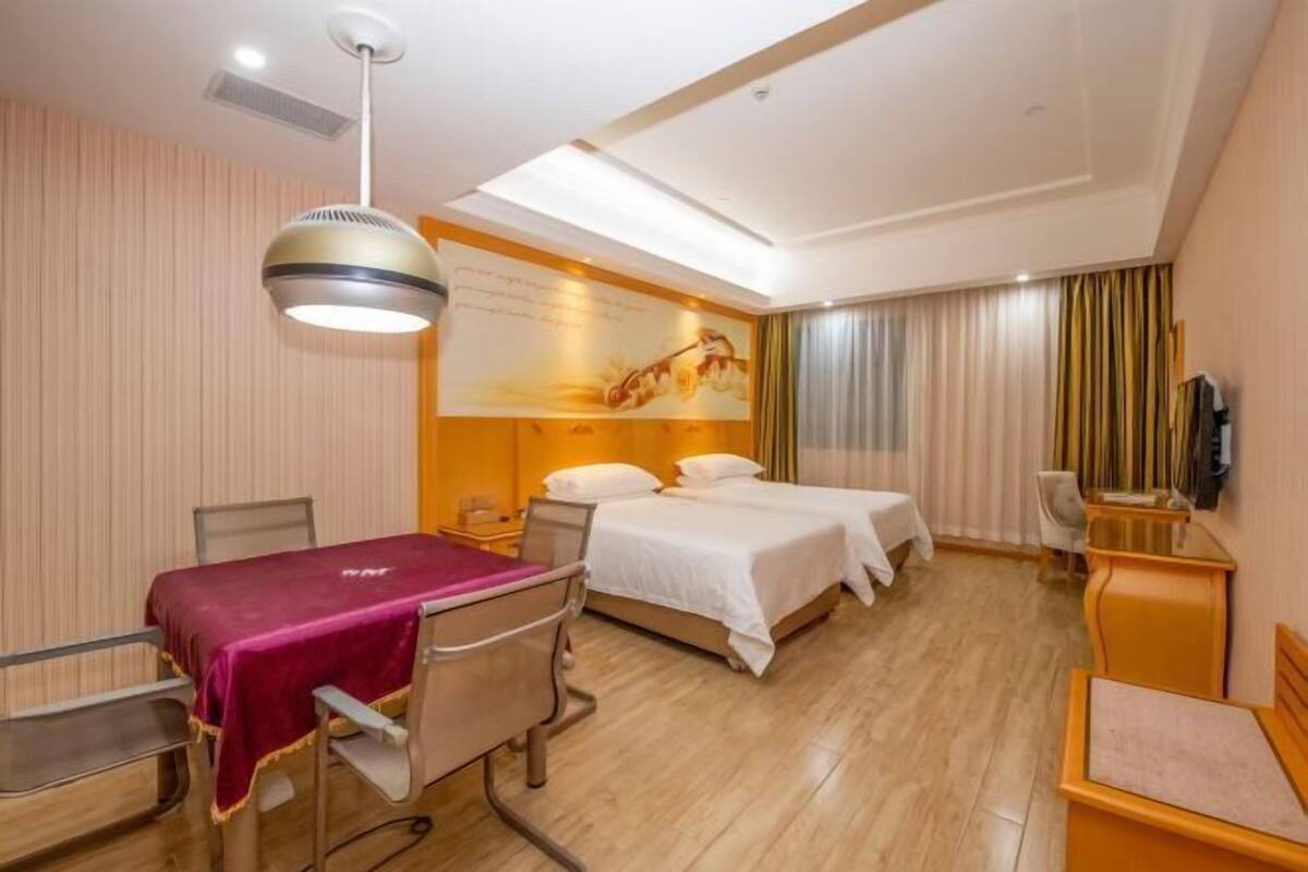 A hotel room with a bed, two bedside tables, a desk with a chair, a TV, and a ceiling light.