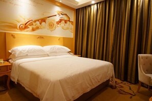 Quarto de hotel com uma cama grande, uma mesa de cabeceira, uma cadeira e uma parede com um mural floral.