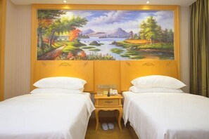 Quarto de hotel com duas camas, um quadro de paisagem na parede e uma pequena mesa de cabeceira de madeira com um telefone.