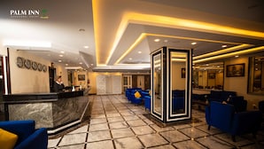 Rebuda d'hotel amb taulell de recepció, zona de seients blava i terra emmotllastada.