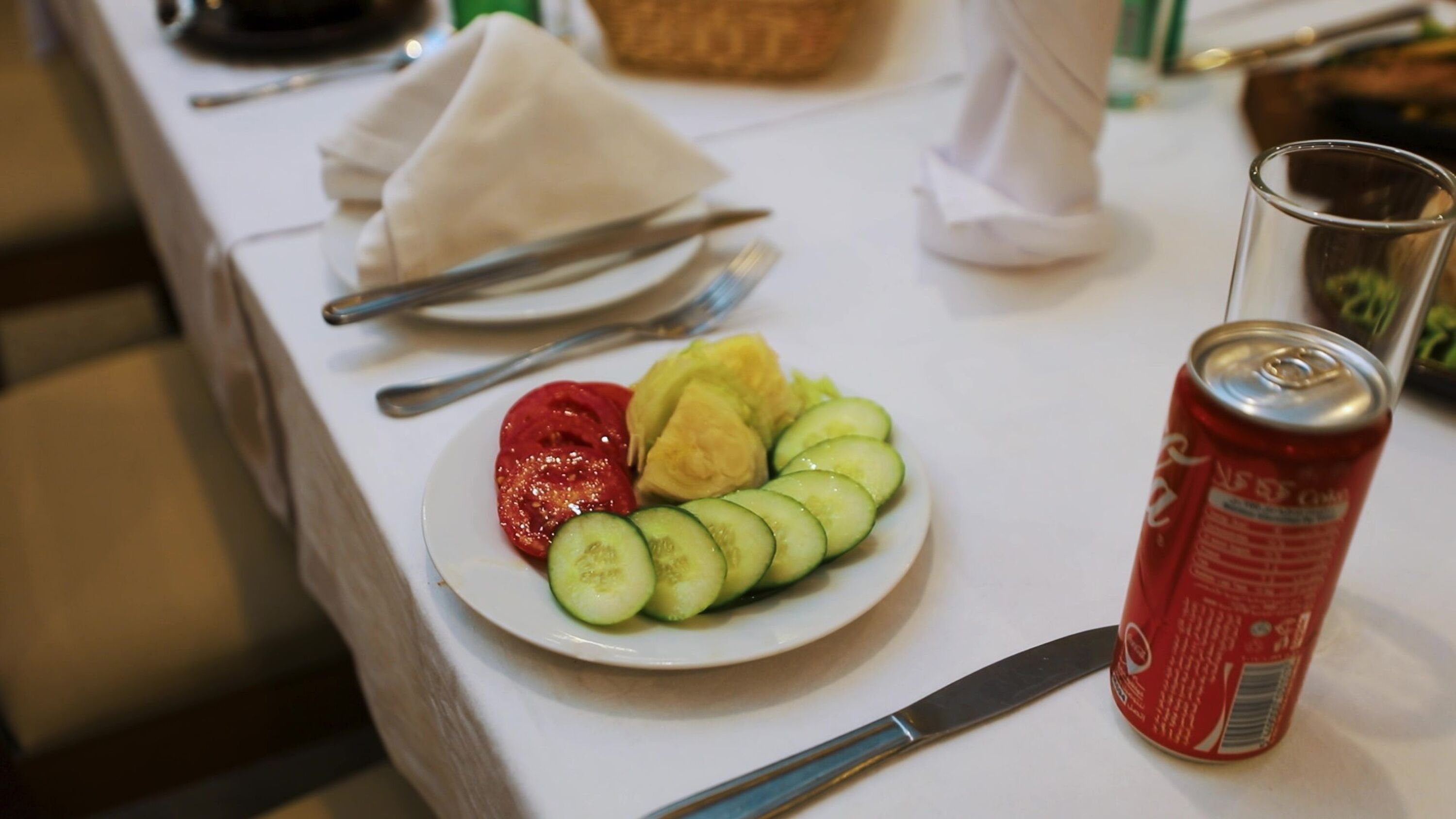 Ein Teller mit Gurkenscheiben, Tomaten und Bananen auf einem Tisch.