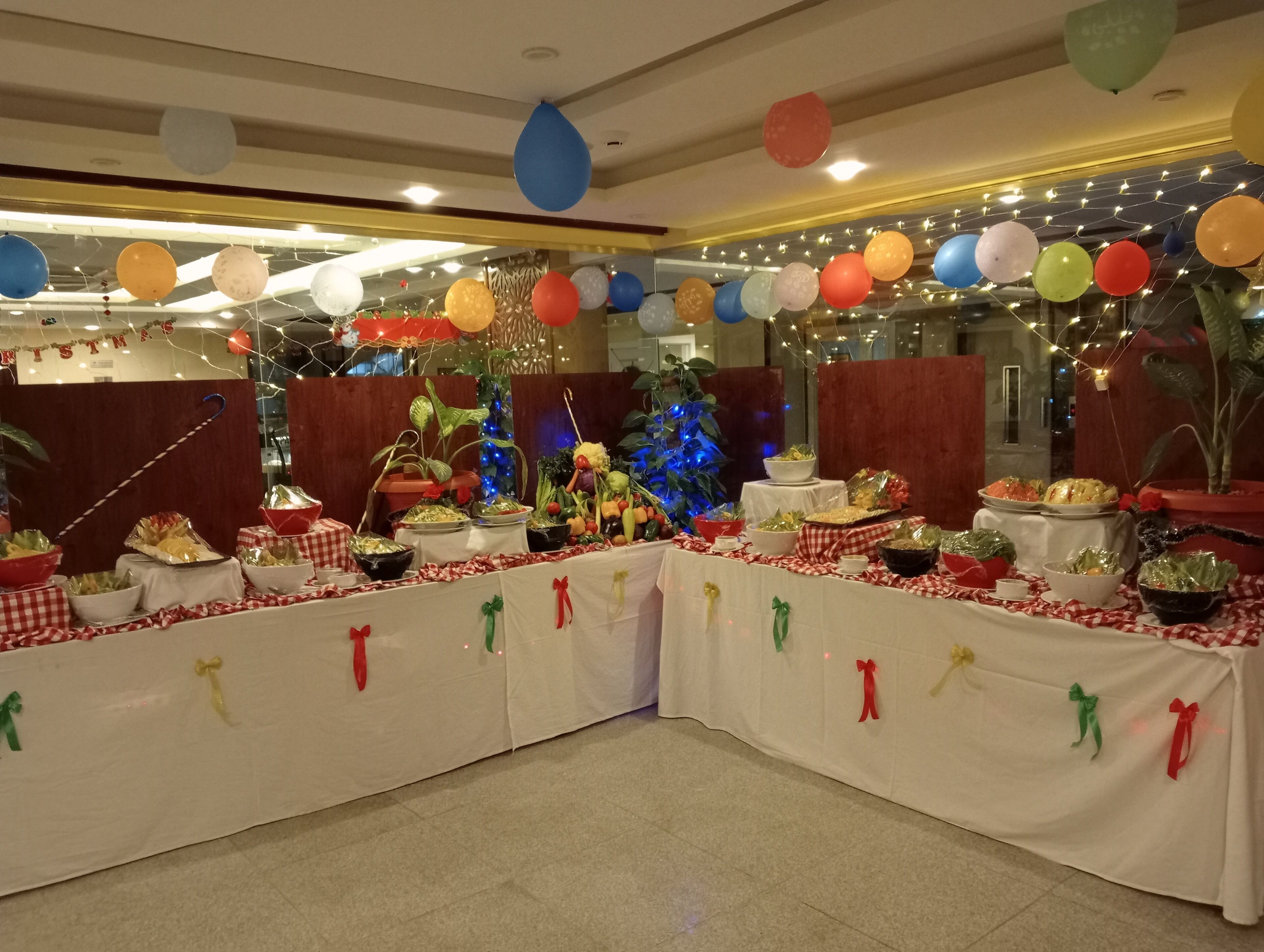 A buffet table with various food items and decorations, including balloons and string lights.