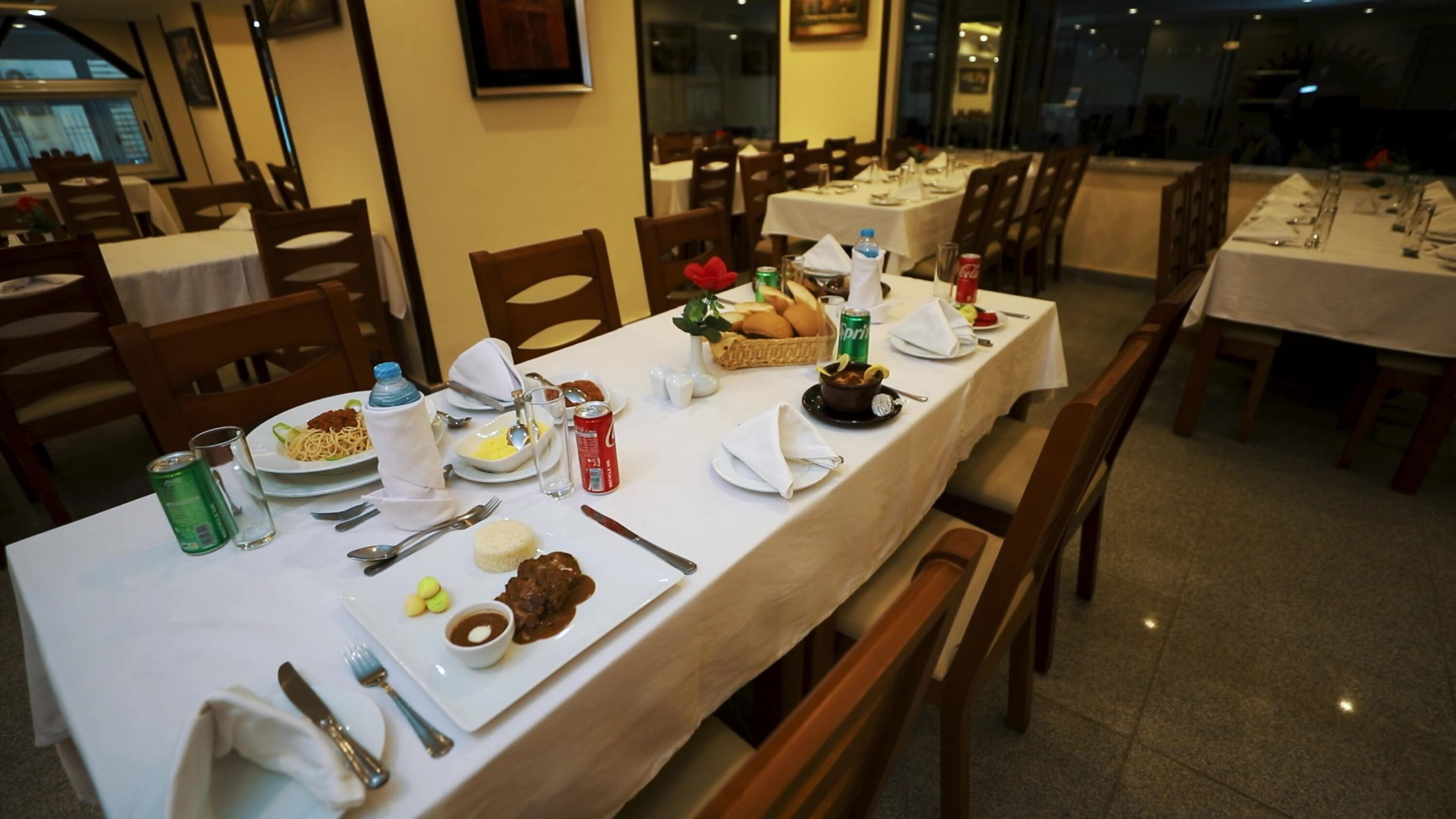 A dining area with tables set for meals, including plates of food, utensils, and condiments.