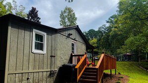 Une maison dotée d’une terrasse en bois et d’un escalier menant à un porche.