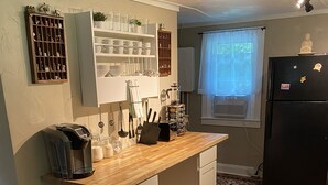 Une cuisine de taille réduite avec un plan de travail en bois, des placards blancs, une poubelle rouge et un tapis à motifs.