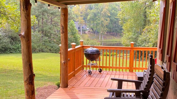 Une terrasse en bois dotée d’un espace couvert, d’un barbecue et d’une rangée de bancs.