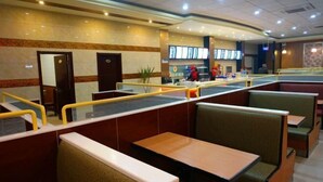 A restaurant with booths and tables, a counter with a menu, and a person in a red uniform. - Super 8 Hotel (Shucheng Chunqiu South Road Cimugong) (Shucheng)