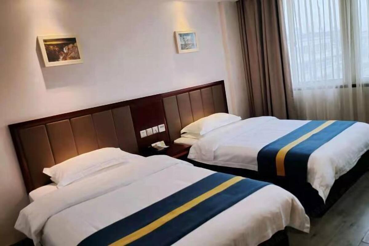 Een hotelkamer met twee bedden, elk met een hoofdeinde en een nachtkastje.