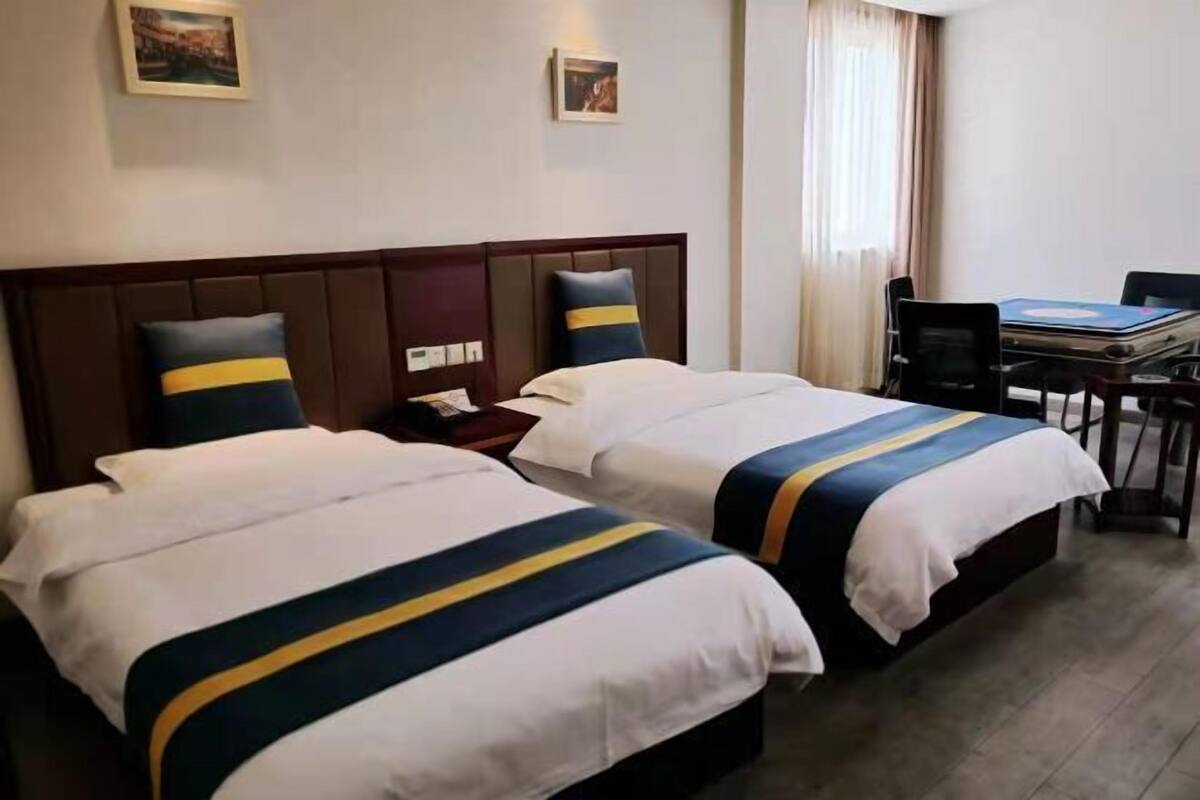 Een hotelkamer met twee bedden, een bureau en een stoel.