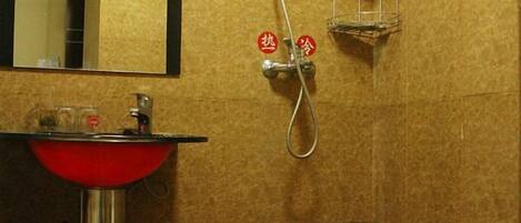 A bathroom with a red sink, a mirror, and a shower with a towel rack.