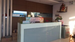 Un espace d’accueil comprenant un comptoir, des affiches d’information, une plante en pot et une étagère murale agrémentée d’objets décoratifs.