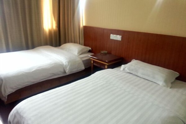 A hotel room with two single beds, a wooden headboard, a nightstand, and a window with curtains. - Haitian Hotel (Wuhu)