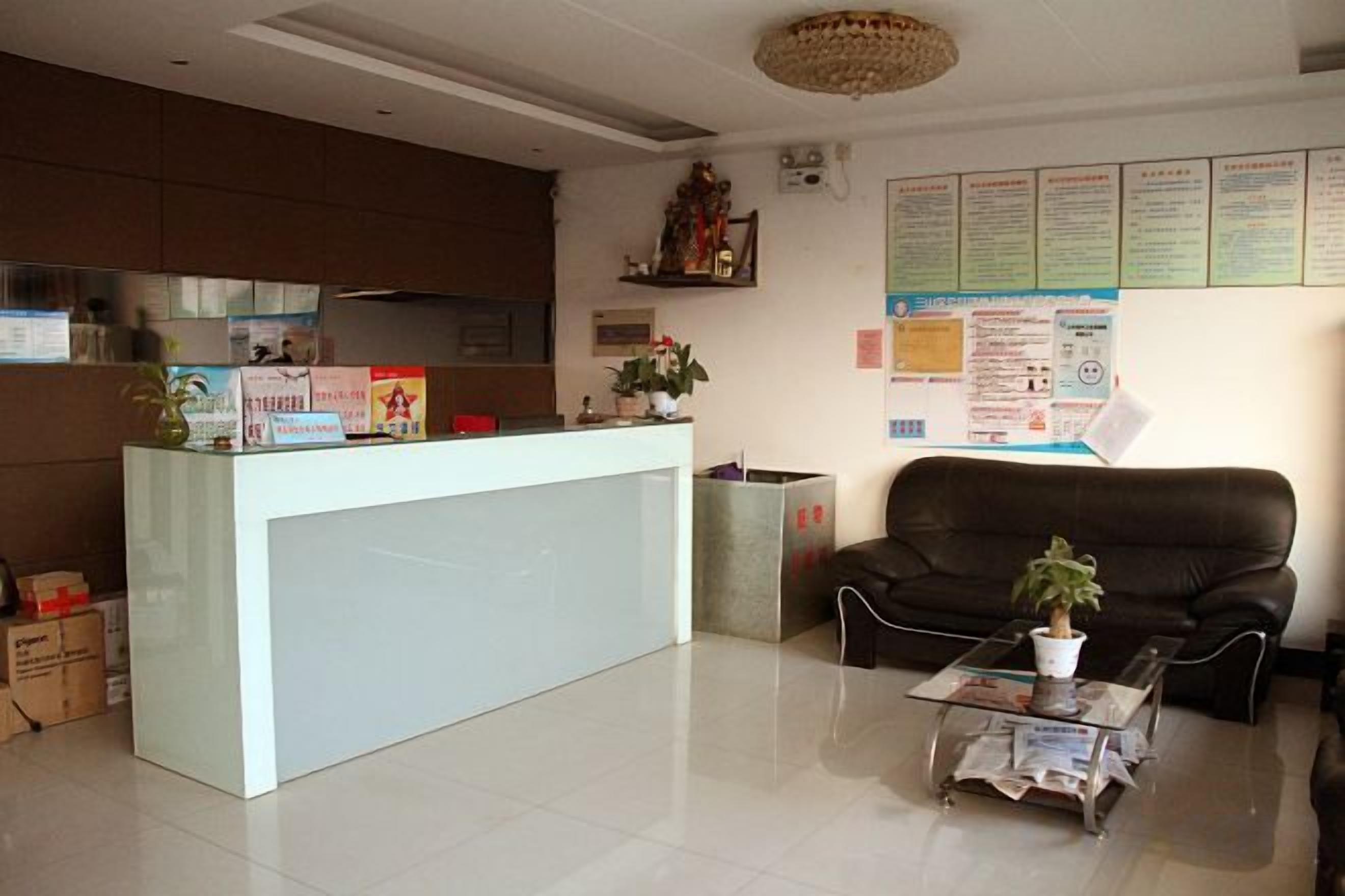 A reception area with a reception desk, a black leather sofa, a coffee table with a plant, and informational posters on the wall.