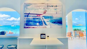 En restaurang med en stor, abstrakt målning av en båt på vattnet, utsikt över havet och en QR-kod som leder till menyn.