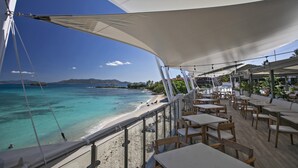 En restaurang vid havet med uteservering som har utsikt över en strand och havet.