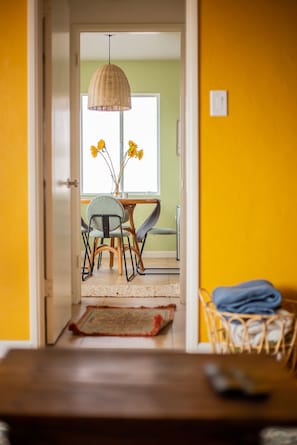 A doorway leading to a dining area with a table and chairs, a hanging light fixture, and a window with flowers. - Cozy Home with Downtown View -- 10 min drive to downtown! (San Diego)